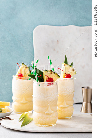 Tropical tiki cocktail pina colada in a fun glass garnished with pineapple Tropical tiki cocktail pina colada in a fun glass garnished with pineapple 113866986