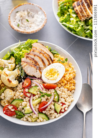 Healthy lunch bowl with grilled chicken, roasted vegetables, fresh lettuce, cooked lentils, salad and boiled egg 113866991