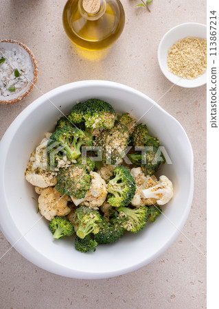 Broccoli and cauliflower florets in a bowl, getting ready to roast vegetables with spices and olive oil Broccoli and cauliflower florets in a bowl, getting ready to roast vegetables with spices and olive oil 113867214