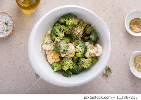 Broccoli and cauliflower florets in a bowl, getting ready to roast vegetables with spices and olive oil 113867215