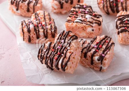 Pink heart shaped rice krispie treats drizzled with dark chocolate on a marble board 113867306