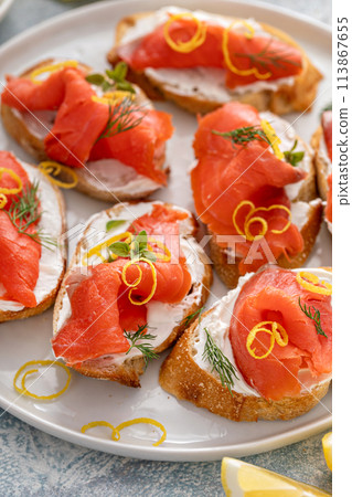 Smoked salmon crostini with cream cheese, dill and lemon zest 113867655