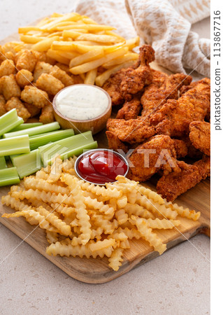 Fried chicken strips and french fries board with sauces and celery Fried chicken strips and french fries board with sauces and celery 113867716