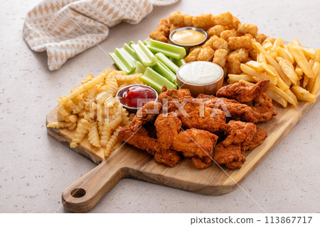 Fried chicken strips and french fries board with sauces and celery 113867717