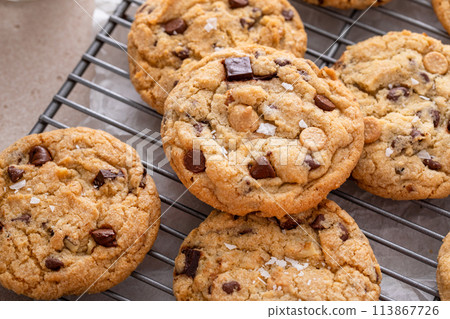 Chocolate chip cookies on a cooling rack with flaky salt served with milk Chocolate chip cookies on a cooling rack with flaky salt served with milk 113867726
