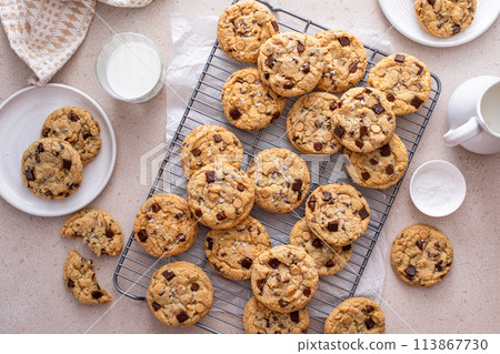 Chocolate chip cookies on a cooling rack with flaky salt served with milk Chocolate chip cookies on a cooling rack with flaky salt served with milk 113867730