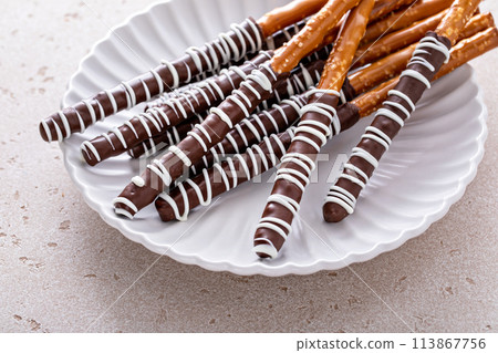 Chocolate dipped pretzel rods on a plate 113867756