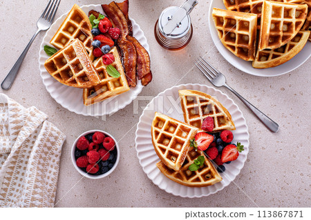 Breakfast table with waffles, bacon, breakfast sausage, croissants and berries 113867871