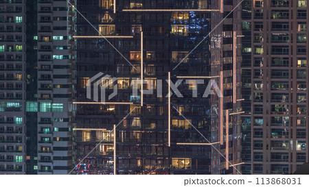 Rows of glowing windows with people in apartment building at night. Rows of glowing windows with people in apartment building at night. 113868031