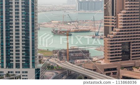 Aerial view to Dubai marina skyscrapers with construction site and Palm Jumeirah Island on background timelapse. Aerial view to Dubai marina skyscrapers with construction site and Palm Jumeirah Island on background timelapse. 113868036