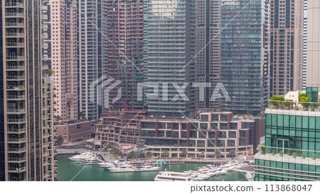 Aerial view of Dubai Marina residential and office skyscrapers with waterfront timelapse Aerial view of Dubai Marina residential and office skyscrapers with waterfront timelapse 113868047