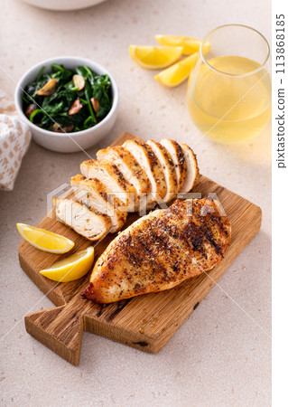 Grilled chicken breast, whole and sliced on a cooking board 113868185