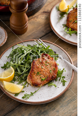 Pork chops served with arugula salad on a plate 113868540