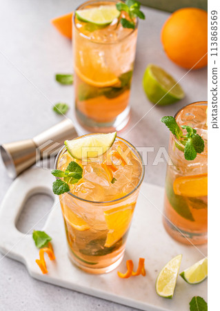 Orange and lime mojito cocktail in tall glasses with lime and mint Orange and lime mojito cocktail in tall glasses with lime and mint 113868569
