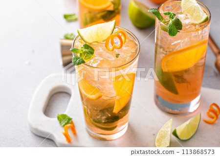 Orange and lime mojito cocktail in tall glasses with lime and mint Orange and lime mojito cocktail in tall glasses with lime and mint 113868573