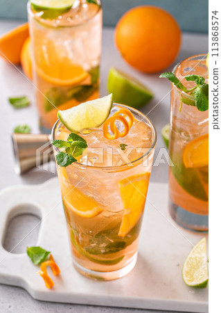 Orange and lime mojito cocktail in tall glasses with lime and mint 113868574