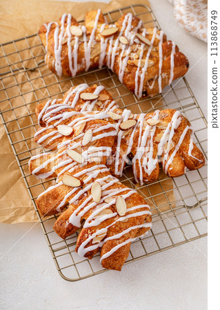 Bear claw pastry on a cooling rack with glaze and almonds 113868749