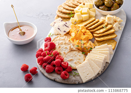 Cheese board or snack board with crackers, cheese, olives and berries 113868775