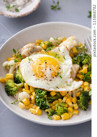 Healthy breakfast bowl with cooked vegetables and fried egg Healthy breakfast bowl with cooked vegetables and fried egg 113868782