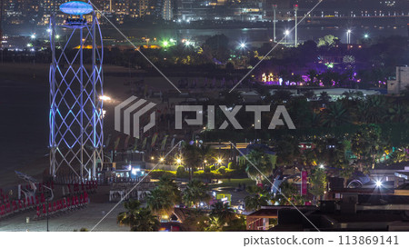 Aerial view of beach and tourists walking in JBR with skyscrapers night timelapse in Dubai, UAE 113869141