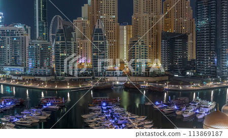Luxury yachts parked on the pier in Dubai Marina bay with city aerial view night to day timelapse 113869187