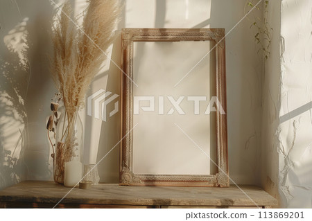 A rectangular picture frame on a hardwood table next to a dried flower vase, mockup 113869201