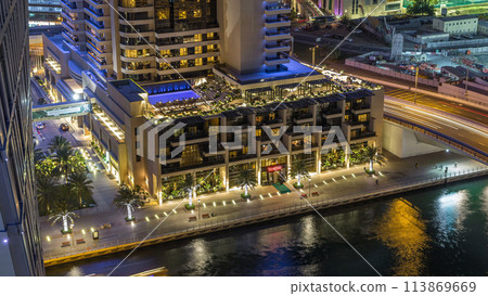 Luxury Dubai Marina canal with passing boats and promenade night timelapse, Dubai, United Arab Emirates 113869669