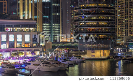 Aerial view of Dubai Marina with shopping mall, restaurants, towers and yachts night timelapse, United Arab Emirates. 113869696