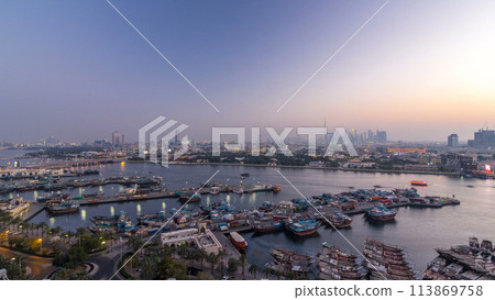 Dubai creek landscape day to night timelapse with boats and ship near waterfront 113869758