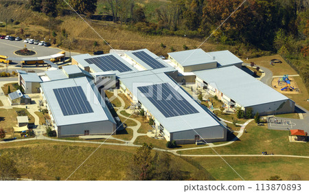 Aerial view of american school building with rooftop covered with photovoltaic solar panels for production of electric energy Aerial view of american school building with rooftop covered with photovoltaic solar panels for production of electric energy 113870893