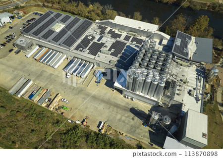 Aerial view of solar power plant with blue photovoltaic panels mounted on industrial building roof for producing green ecological electricity. Production of sustainable energy concept Aerial view of solar power plant with blue photovoltaic panels mounted on industrial building roof for producing green ecological electricity. Production of sustainable energy concept 113870898