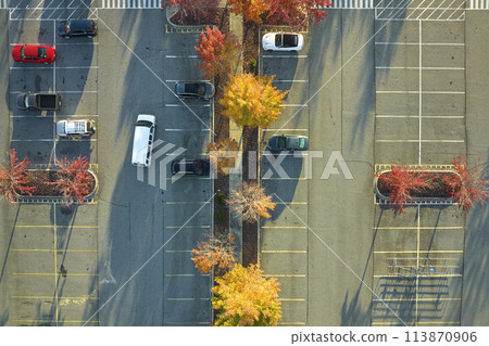 Aerial view of large parking lot with many parked colorful cars. Carpark at supercenter shopping mall with lines and markings for vehicle places and directions Aerial view of large parking lot with many parked colorful cars. Carpark at supercenter shopping mall with lines and markings for vehicle places and directions 113870906