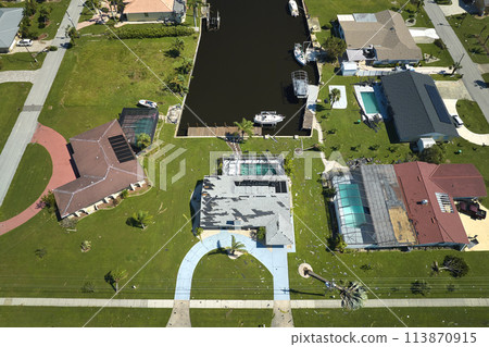 Damaged house roof with missing shingles after hurricane Ian in Florida. Consequences of natural disaster 113870915
