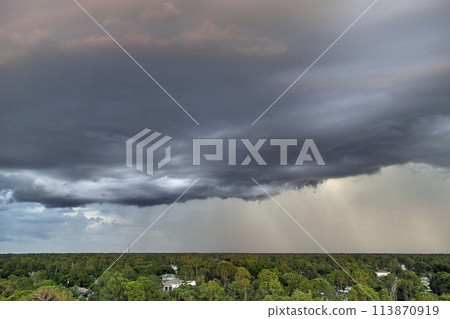 Landscape of dark ominous clouds forming on stormy sky during heavy thunderstorm over rural town area at sunset Landscape of dark ominous clouds forming on stormy sky during heavy thunderstorm over rural town area at sunset 113870919