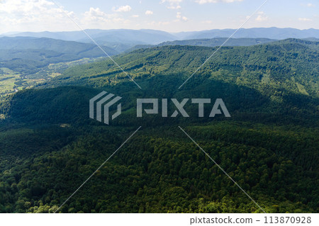 Aerial view of mountain hills covered with dense green lush woods on bright summer day. Aerial view of mountain hills covered with dense green lush woods on bright summer day. 113870928
