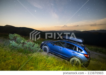 Blue offroad SUV car with roof trunk on background of very beautiful night starry sky after sunset. Freedom and travel by car concept 113870983
