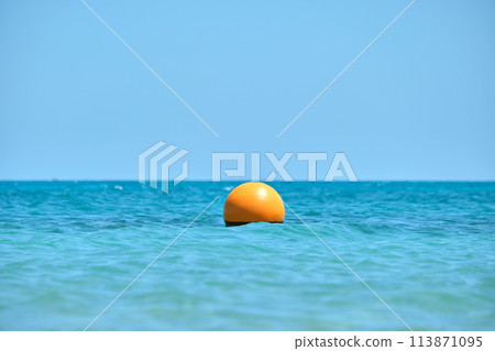 Orange buoy floating on sea surface waves. Human life safety concept. Orange buoy floating on sea surface waves. Human life safety concept. 113871095