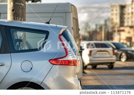 Modern cars parked on a side of a city street on a sunny day. 113871176