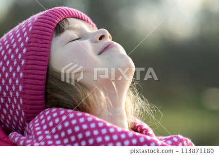 Pretty child girl in warm knitted winter clothes outdoors. 113871180