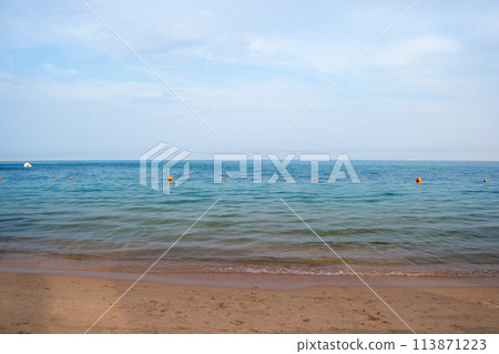 Seascape with surface of blue sea water with small ripple waves crashing on yellow sandy beach. Travel and vacations concept. 113871223