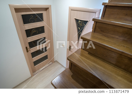 Interior of a house or appartment hallway with oak wooden stairs and room doors. Interior of a house or appartment hallway with oak wooden stairs and room doors. 113871479