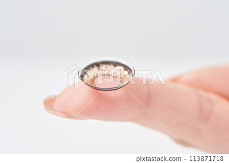 Woman's finger holding colored contact lenses 113871718