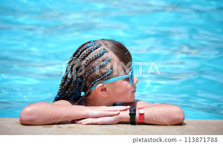 Young joyful child girl resting on swimming pool side with clear blue water on sunny summer day. Tropical vacations concept Young joyful child girl resting on swimming pool side with clear blue water on sunny summer day. Tropical vacations concept 113871788