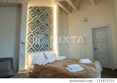 Interior of a spacious hotel bedroom with fresh linen on a big double bed. Cozy contemporary room in a modern house. 113872723