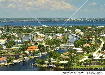 Aerial view of rural private houses in remote suburbs located on sea coast near Florida wildlife wetlands with green vegetation on gulf bay shore. Living close to nature in tropical region concept Aerial view of rural private houses in remote suburbs located on sea coast near Florida wildlife wetlands with green vegetation on gulf bay shore. Living close to nature in tropical region concept 113872858