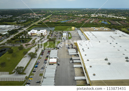 Top view of giant logistics center with many commercial trailer trucks unloading and uploading retail products for further shipment. Global economy concept 113873431