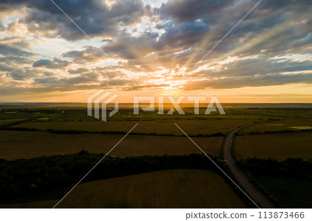 Aerial view of intercity road with fast driving cars between farmland fields at sunset. Top view from drone of highway traffic in evening 113873466