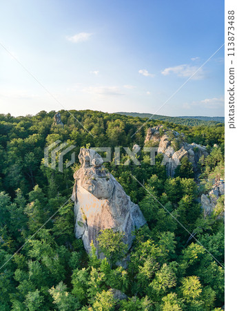 Aerial view of bright landscape with green forest trees and big rocky boulders between dense woods in summer. Beautiful scenery of wild woodland. Aerial view of bright landscape with green forest trees and big rocky boulders between dense woods in summer. Beautiful scenery of wild woodland. 113873488