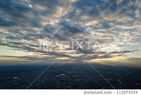 Aerial view from airplane window at high altitude of distant city covered with puffy cumulus clouds forming before rainstorm Aerial view from airplane window at high altitude of distant city covered with puffy cumulus clouds forming before rainstorm 113873554