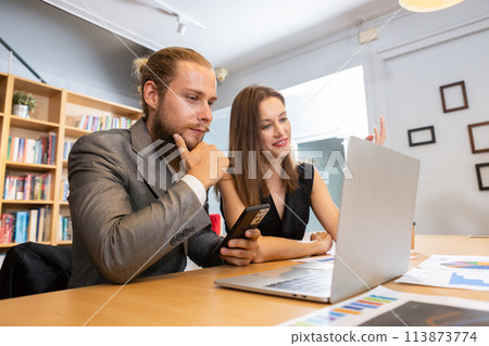 Two businesspeople brainstorming talking looking document in laptop. Two businesspeople brainstorming talking looking document in laptop. 113873774